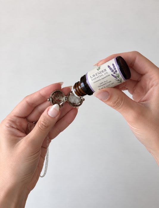 Mãos pingando óleo essencial de lavanda num colar difusor pessoal